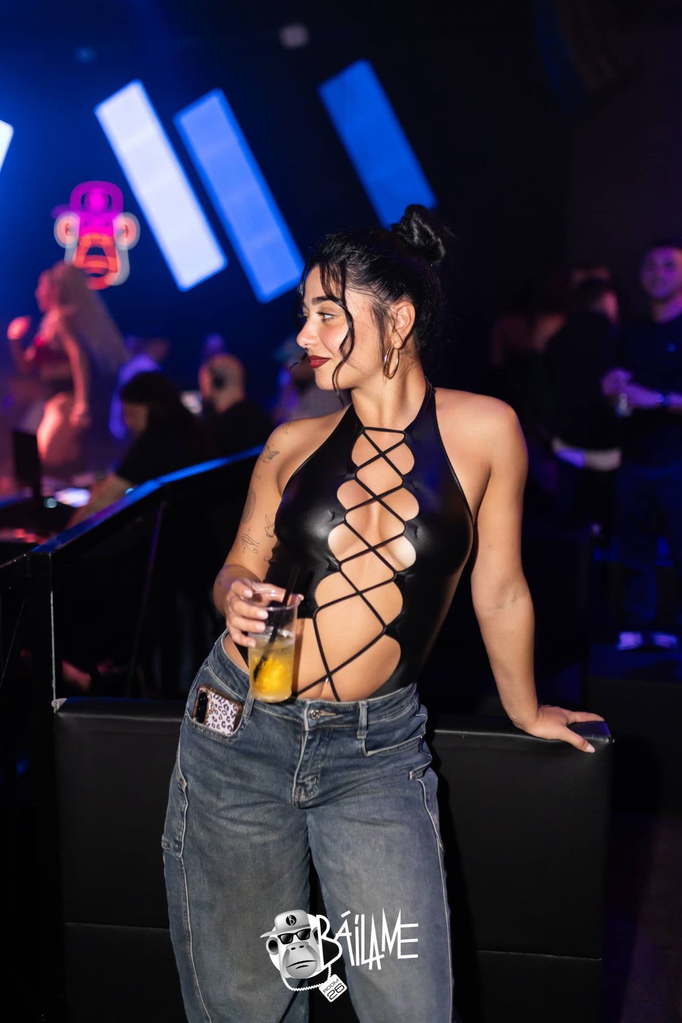 Una ragazza con un drink in mano si guarda intorno