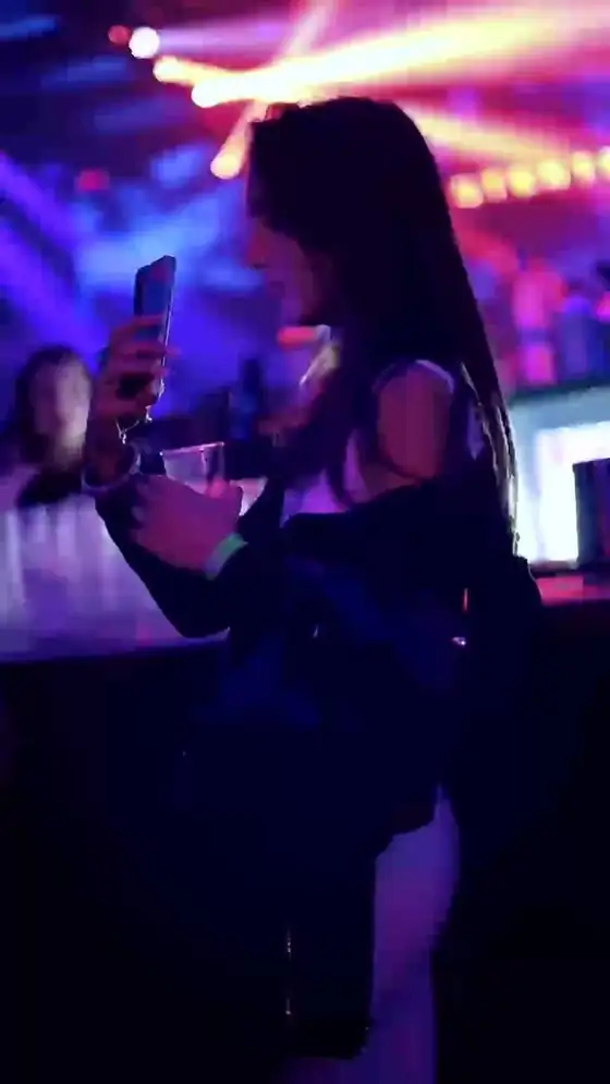Una ragazza al bancone con il drink in mano