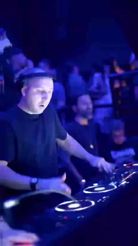 Il dj alla consolle, con la sala illuminata di blu alle spalle