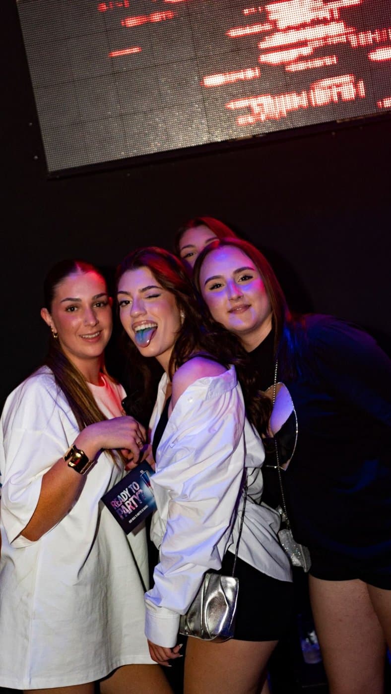 Tre amiche con i drink in mano fanno le linguacce